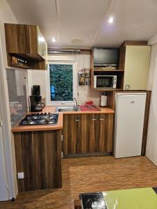 Magnifique Mobil home Lac D'Aiguebelette في Novalaise: مطبخ بدولاب خشبي وثلاجة بيضاء