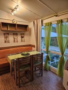 - un salon avec une table, un canapé et une fenêtre dans l'établissement Magnifique Mobil home Lac D'Aiguebelette, à Novalaise
