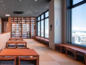 eine Bibliothek mit Bänken, Bücherregalen und Fenstern in der Unterkunft REF Kanku-Izumisano by VESSEL HOTELS in Izumi-Sano