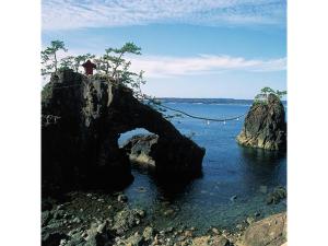 a person standing on a rock in the water at Bokkai Onsen Seaside Villa Bokkai - Vacation STAY 69010v in Shika