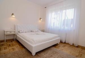 a white bedroom with a white bed and a window at Elena in Palanga