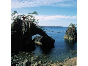 a person standing on a rock in the water at Bokkai Onsen Seaside Villa Bokkai - Vacation STAY 69023v in Shika