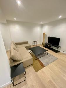 uma sala de estar com um sofá e uma televisão de ecrã plano em Loft Rochegude em Albi