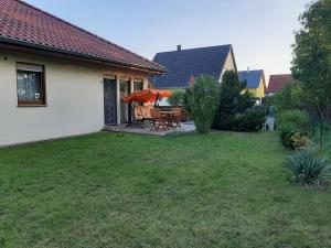 a yard with a patio with a table and umbrella at Ferienhaus am Kulkwitzer See in Leipzig