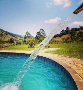 ein Wasserlauf, der in ein Schwimmbad strömt in der Unterkunft Rancho Maria Pimenta in Joanópolis