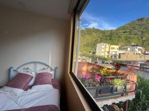 a bedroom with a bed and a window with a view at Hospedaje Charlie's House in Baños