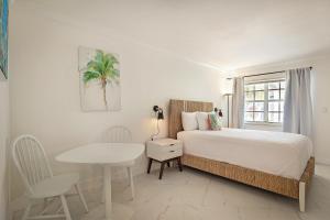 a white bedroom with a bed and a table at La Mer Suites in Fort Lauderdale