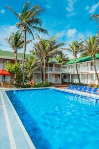 una piscina con sillas y palmeras frente a un hotel en Decameron San Luis - All Inclusive en San Andrés