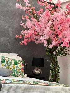 een vaas gevuld met roze bloemen naast een bed bij B&B i MORI in Catania