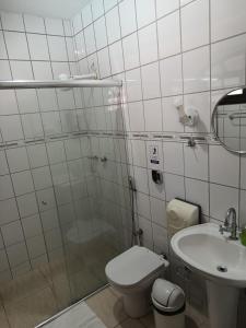 a white bathroom with a toilet and a sink at Pousada Nascente do Pirahy in Piraí