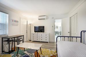 een slaapkamer met een bed en een tafel en een televisie bij La Mer Suites in Fort Lauderdale