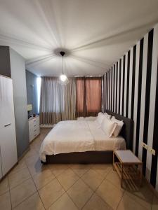 Dormitorio con cama con pared de rayas en blanco y negro en Ergi’s Host Apartment, en Tirana