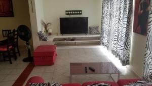 a living room with a television and a red couch at Condo Penthouse Batey Dominicus in Bayahibe