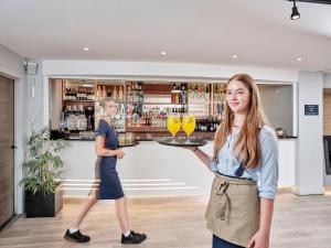 dos mujeres de pie en un bar sosteniendo vasos en Sandy Cove Hotel en Ilfracombe