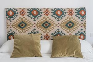 a bed with two pillows in front of a wall at Luxury Apartment Free Parking in Seville