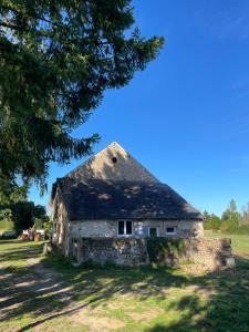 eine alte Scheune auf einem Feld mit einem Baum in der Unterkunft Belle vue in Saint-Silvain-Bas-le-Roc