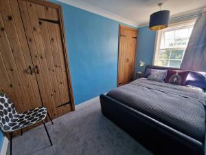 1 dormitorio azul con 1 cama y 1 silla en Number One Bridgefoot Cottage en West Stockwith