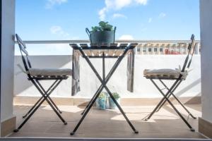 two chairs and a table with a plant on a balcony at Luxury Apartment Free Parking in Seville