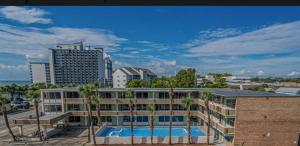 a building with a swimming pool in front of a city at Palmsbythebeach in Myrtle Beach