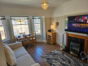 a living room with a couch and a tv at Harbour View Apartment in Llandrillo-yn-Rhôs