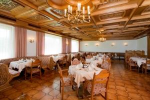 una sala da pranzo con tavoli, sedie e lampadario a braccio di Hotel Fantur a Velden am Wörthersee