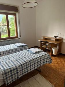 a room with two beds and a desk and a table at B&B PRETITE in Artegna