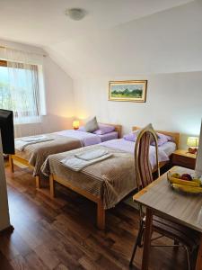 1 dormitorio con 2 camas, mesa y sofá en Rooms Vukša, en Donji Lapac