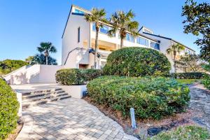 a white building with palm trees and bushes at Captains Court 1031 in Fernandina Beach