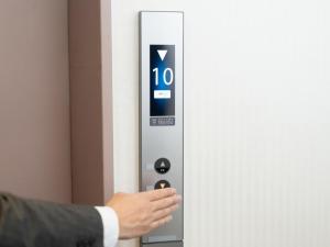 鳥栖市にあるSun Hotel Tosu Saga - Vacation STAY 49476vのスーツ姿の男がエレベーターのボタンを押している