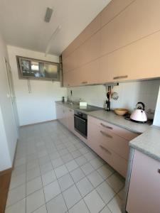 a kitchen with brown cabinets and a white tile floor at Apartament Salwator Fałata in Krakow