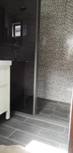 a bathroom with a shower and a tiled wall at Bij BRAKKE in Paramaribo