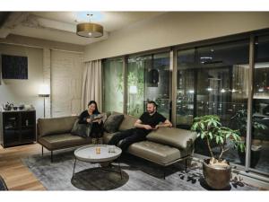 two people sitting on a couch in a living room at THE BOLY OSAKA - Vacation STAY 52036v in Osaka