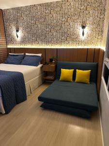 ein Schlafzimmer mit einem Bett und einem Sofa mit gelben Kissen in der Unterkunft Loft de Luxo no Bairro mais nobre de Goiânia in Goiânia