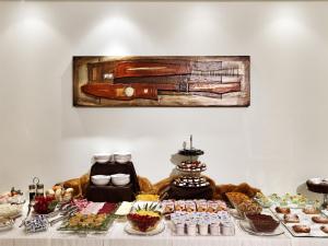 une table remplie de nourriture et une peinture sur le mur dans l'établissement All Time Relais & Sport Hotel, à Rome