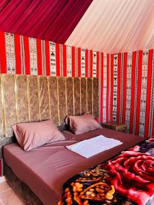 a bed in a tent with red and red walls at wadi rum camp stars & jeep tour in Wadi Rum