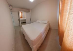 Habitación pequeña con cama blanca. en Apartamento Residencial Bordô amplo 3 quartos próximo à praia, en Itapema