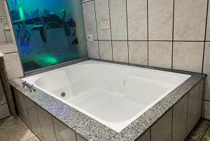 uma grande banheira branca na casa de banho em MOTEL 2000 em São Paulo