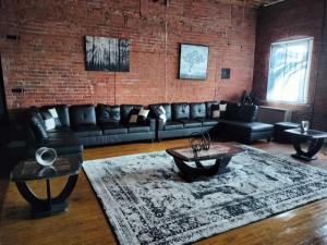 a living room with leather couches and a brick wall at Idlewild Villa Loft apts in Detroit