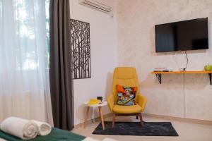 a living room with a yellow chair and a television at NEW Iorga3 OldCity SelfCheckIn in Timişoara