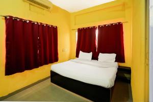 a bedroom with a large bed with red curtains at Hotel Supreet Inn in Raipur