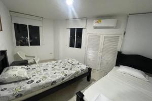 1 dormitorio con 2 camas, silla y ventanas en Apartamento hermosa Vista al Mar en el Rodadero Santa Marta, en Santa Marta