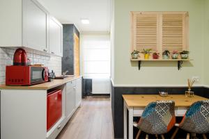 蒂米什瓦拉的住宿－NEW Iorga4 OldCity SelfCheckIn，厨房配有白色橱柜和木桌