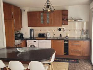a kitchen with wooden cabinets and a table and chairs at Belle maison spacieuse proche Genève et CERN in Saint-Genis-Pouilly