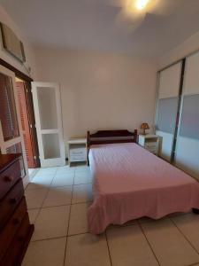 a bedroom with a bed with a pink bedspread at Apart-hotel Marinas do Canal in Cabo Frio