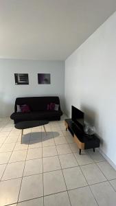 a living room with a black couch and a table at Superbe T2 à Balaruc les Bains in Balaruc-les-Bains