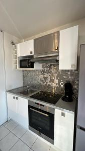 a kitchen with white cabinets and a stove top oven at Superbe T2 à Balaruc les Bains in Balaruc-les-Bains