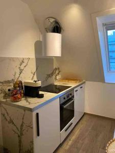 a white kitchen with a stove and a sink at Moderne studio in Nieuwpoort