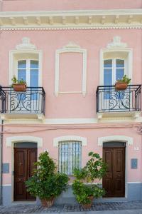a pink building with windows and potted plants at Sa ia Suite 2 in Cagliari