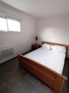 1 dormitorio con cama grande de madera y ventana en Gîte entre mer et montagne, en Saint-Vincent