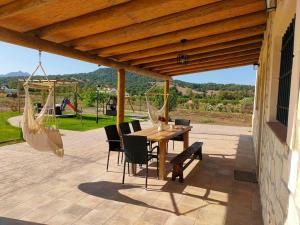 un patio con mesa, sillas y un columpio en Valle de la Rosa en Prado del Rey